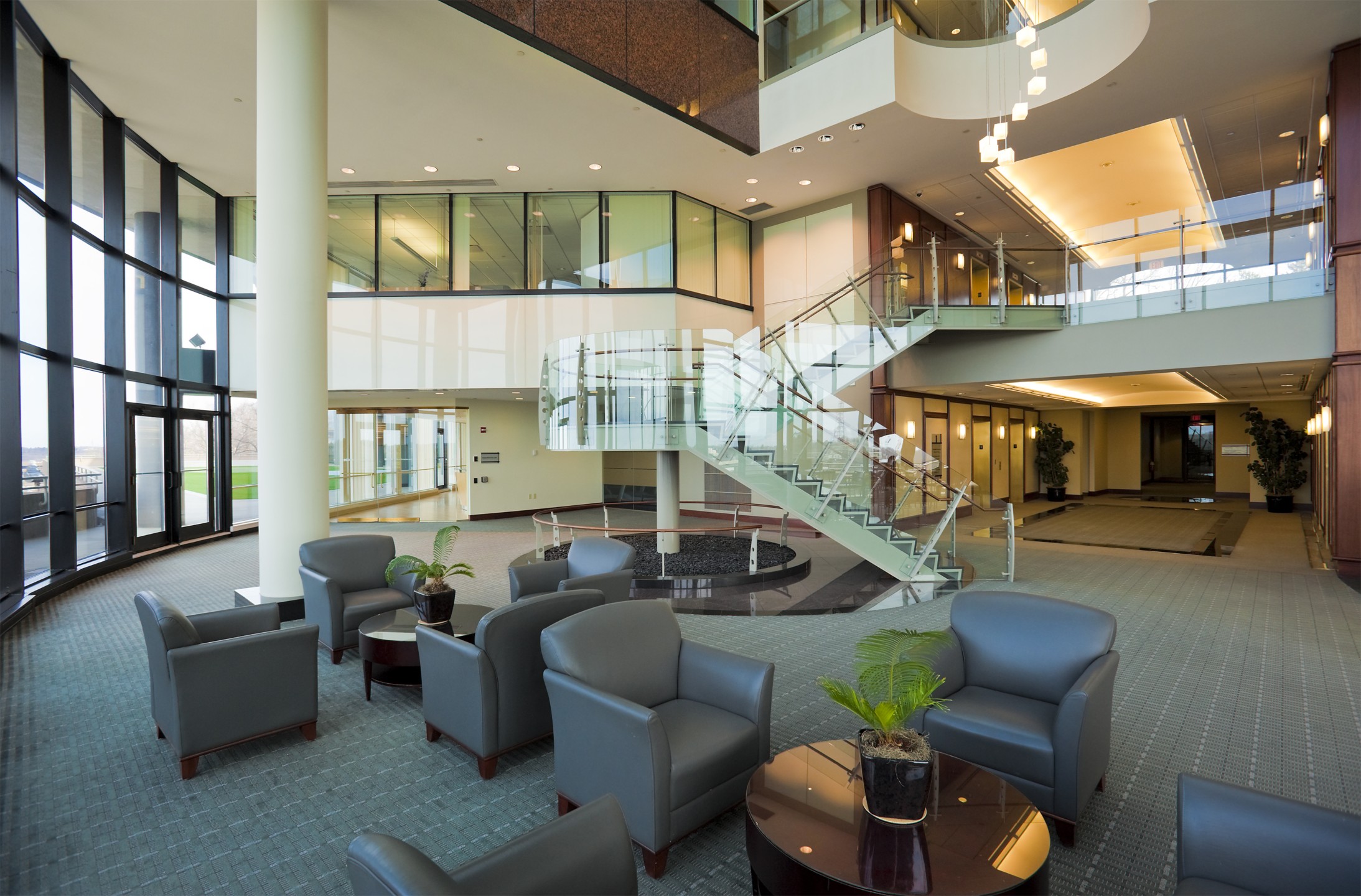 A large multi-story office lobby with seating and a wall of windows.